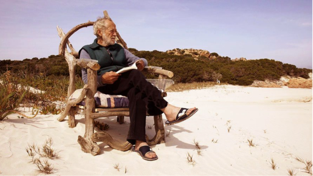 Old man in a chair on a beach in Italy - pink sand beach