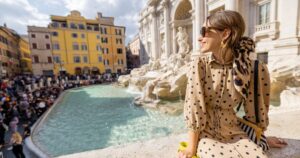 Beautiful woman sitting beside the Trevi Fountain in Rome, Italy